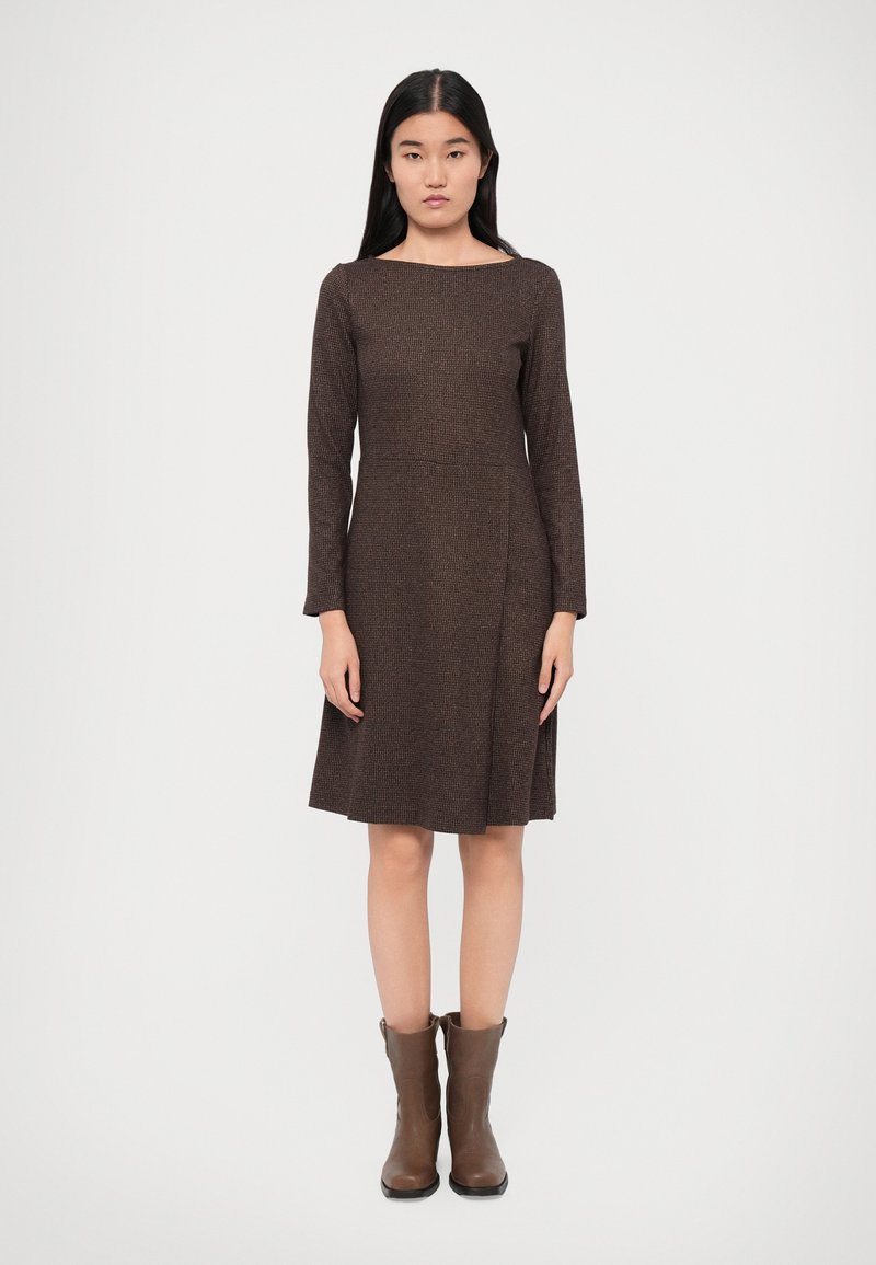 Brown, long-sleeve dress with a square neckline and A-line shape, made of textured fabric. Paired with brown ankle boots.