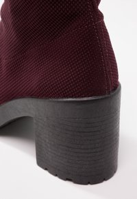 Burgunderfarbene, strukturiert Ankle Boots mit einem klobigen Gummifreigang, der vertikale Rillen aufweist. Das Obermaterial ist aus gewebtem Stoff.