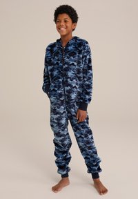 Zilā kamuflāžas raksta flīsa kombinzona ar kapuci, ar rāvējslēdzēju priekšpusē un ribotām aprocēm. Izceļas ar mīkstu tekstūru un brīvu piegriezumu ērtībai.