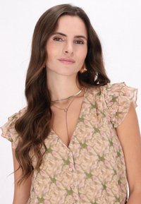 Blomsterkjole med flæser på ærmerne i pastelfarverne pink og grøn, med en V-hals og knapdetalje, suppleret med lagdelte halskæder.