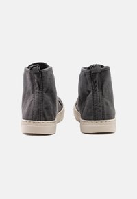 Zapatos de lona gris de caña alta con un acabado texturizado y una suela de goma beige en contraste. Con una lengüeta en la parte trasera para facilitar su uso.