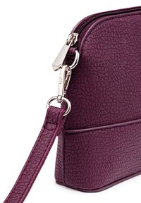Purple textured handbag, featuring a zip closure, silver hardware accents, and a detachable strap. Compact design with structured shape.