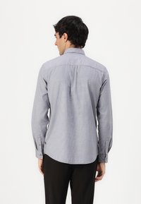 Lange mouwen shirt in lichtblauw met een subtiele ruitpatroon. Voorzien van een standaard kraag, knoopmanchetten en een gebogen zoom. Gelaagd stof.