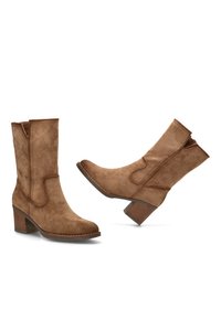 Botas de tobillo de ante marrón con un diseño de costura lateral curva, punta redonda y un tacón de bloque medio con un acabado texturizado similar a la madera.