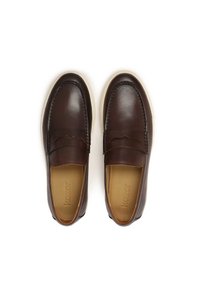Zapatos de piel marrón sin cordones con un acabado suave, puntera redondeada y suela de goma blanca. Presentan costuras decorativas y un diseño de acento sutil.