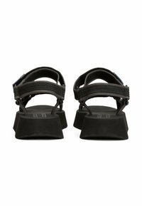 Sandalias de plataforma negras con suelas de goma gruesa y correas de nylon ajustables. Diseño minimalista con una superficie de correa texturizada.