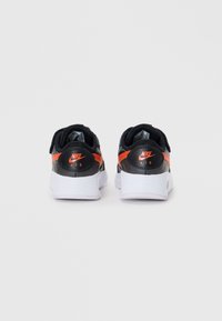 Fekete és narancssárga Nike Air cipők, textúrált felsőrésszel, fehér talppal és figyelemfelkeltő Nike logóval a saroknál.