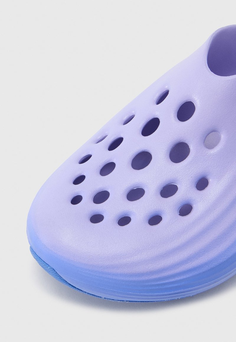 Light purple slip-on shoe with multiple circular ventilation holes and a textured sole on a white background.