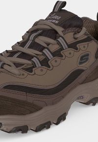 Καφέ και μαύρο πεζοπορικό παπούτσι Skechers με άνοιγμα για κορδόνια και ανθεκτική σόλα σχεδιασμένη για υπαίθρια χρήση.