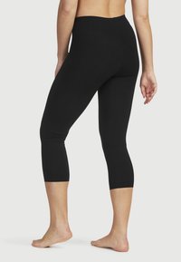 Svarta korta leggings gjorda av ett följsamt, elastiskt tyg med hög midja. Har en figurnära design och sömlös konstruktion.