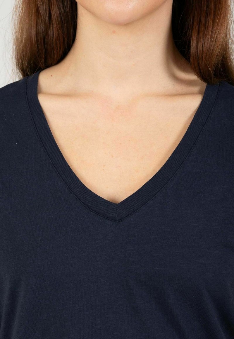 Camiseta azul marino de cuello en V hecha de tela suave, con un ajuste relajado y textura lisa, con un diseño de escote limpio y sencillo.