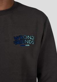 Felpa grigio scuro con collo a coste, con logo ricamato blu e turchese "WRONG FRIENDS DESIGN HOUSE" sul petto.
