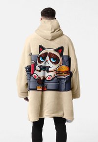 Beige oversized hoodie with a cartoon cat design on the back, featuring a couch, snacks, and gaming controller. Smooth texture, casual fit.