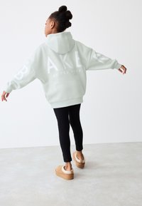 Heleheledat tooni roheline suures mõõdus kapuutsiga pusa suure valge trükiga, pehme kangas, soonikkoes mansetid, kombineeritud mustade retuuside ja beežide platvormkingadega.