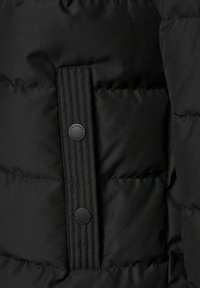 Czarna kurtka puchowa wykonana z fakturowanego materiału, z pionowym, prążkowanym paskiem oraz okrągłymi guzikami z detalami marki. Widoczne pikowane sekcje.