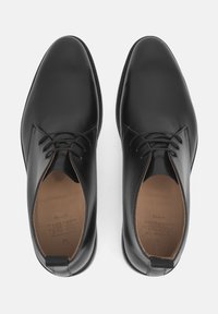 Scarpe eleganti da uomo in pelle nera con finitura liscia, design con lacci, punta arrotondata e interno beige. Suola in gomma nera con minimo battistrada.