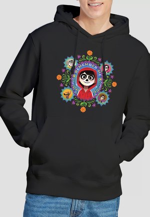Schwarzer Hoodie mit farbenfrohem Blumendesign, das eine Figur mit Skelettgesicht in roter Kapuze umgibt, darüber die Worte "Remember Me".