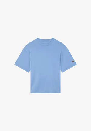 T-shirt bleu clair à manches courtes avec col rond et petit patch circulaire sur la manche gauche, présenté sur fond blanc.