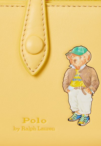 Yellow leather handbag with a bear graphic wearing a green cap and brown jacket. Features embossed "Polo by Ralph Lauren" text.