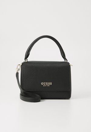 Czarna torebka Guess o fakturowanej powierzchni, z górnym uchwytem, odpinanym paskiem na ramię oraz złotym logo "GUESS EST 1981" na klapie zamykającej przednią część.