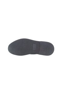 Suela de zapato de goma negra con superficie texturizada, punta redondeada y sección de tacón suave. Presenta un pequeño área rectangular para etiqueta.