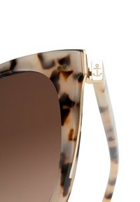 Sköldpaddsformade solglasögon med bruna linser, detaljer i guldmetall och en distinkt ankarmärke på bågen. Vinklad cat-eye design.