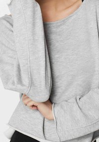 Sweat-shirt gris doté d'un tissu doux et texturé, d'une silhouette oversize, d'un large décolleté et de poignets côtelés avec un ourlet incurvé.