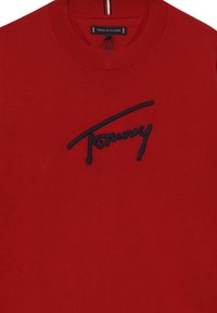 Felpa rossa in cotone con scollo rotondo e polsini a costine. Presenta un logo ricamato in blu navy sul davanti e un dettaglio a righe nel colletto.