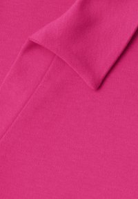 Tissu rose vif avec un détail de col plié, montrant une texture lisse, étroitement tissée et une couleur vibrante.