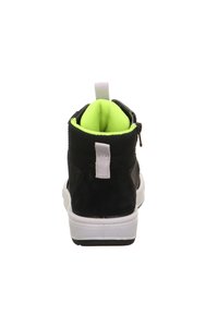 Černé vysoké tenisky s texturovaným povrchem, které mají jasně zelené podšívku, bílou podrážku a poutko na zadní straně.