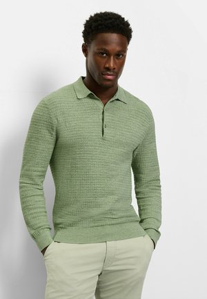 Hellgrünes langärmeliges Poloshirt mit strukturiertem Muster, Knopfleiste und klassischem Kragen, kombiniert mit beigen Hosen.