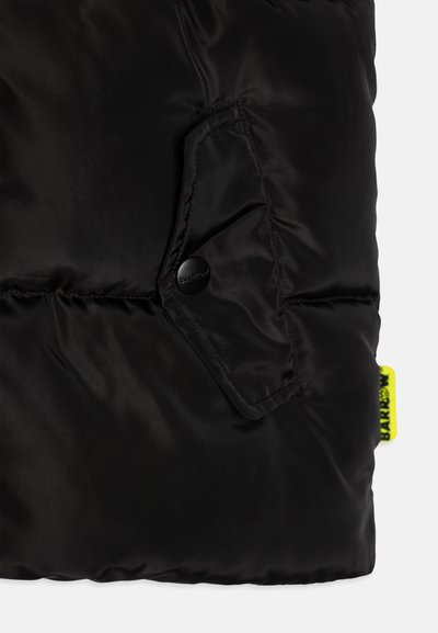 Svart pufferjacka med detaljer som en strukturerad, glänsande tyg, en sidoficka med tryckknapp och en ljusgul märkesetikett.