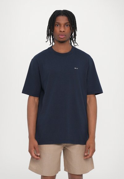 T-shirt à manches courtes bleu marine avec un col rond et un petit logo blanc sur la poitrine. Le matériau semble doux et lisse.