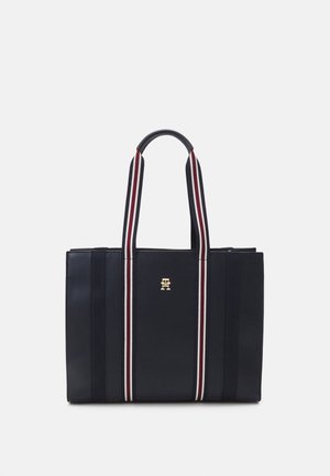 Czarna torba na ramię z pionowymi, biało-czerwonymi paskowanymi uchwytami oraz złotym logo na środku przodu.