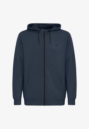 Tume sinine kapuutsiga jakik, millel on ees lukk, reguleeritava kapuutsi nöör ja taskud ees, ning soonikukujulised varrukaotsad. Üksuse vasakul ülemisel küljel on logo.