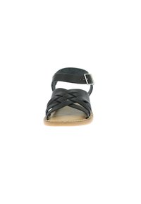 Sandale en cuir noir avec des bandoulières tressées, une seule sangle à la cheville avec une boucle et une semelle beige. Texture lisse avec un minimum de détails.
