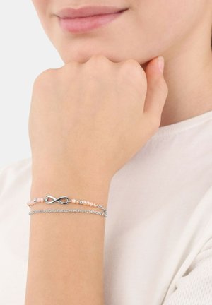 Bracciale in tonalità argento con perle rosa e design a simbolo dell'infinito, sovrapposto a una delicata catena. Texture liscia e stile minimalista.
