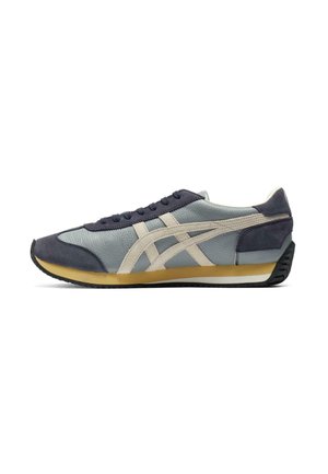 Sneaker with a blue leather and navy suede upper, cream-colored stripes, textured surfaces, and a black rubber sole with a yellow accent.
