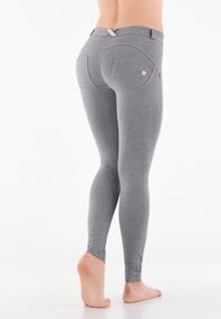 Leggings grigi realizzati in materiale elastico, con un design aderente, dettagli delle cuciture accentuati e tasche posteriori sottili. Texture liscia.