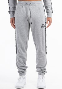 Graue Sweatpants aus weichem Stoff, mit elastischen Bündchen, einem verstellbaren Bund und schwarzen Seitenstreifen mit Branding-Details.