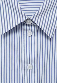 Chemise rayée bleu et blanc avec un col pointu, comportant quatre boutons blancs, tissu lisse, et des rayures verticales espacées uniformément.