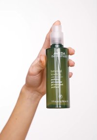 Grön glasflaska med pumplock märkt "botanical kinetics purifying gel cleanser." Kapacitet: 5 fl oz (150 ml). Slät textur.