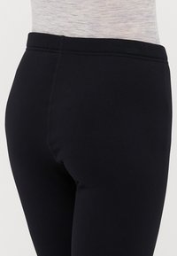 Leggings neri con una finitura liscia e elastica. Presentano un elastico in vita alto e cuciture piatte per il massimo comfort. Design semplice, senza motivi visibili.