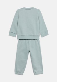 Σετ φούτερ μακρυμάνικο σε γαλάζιο χρώμα και παντελόνι με ελαστική μέση, τοποθετημένα επίπεδα με την πίσω όψη του ρούχου ορατή σε λευκό φόντο.