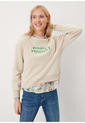 Beige sweatshirt met groene tekst "positive MINDSET", gestructureerde stof, ronde halslijn en een gelaagde bloempatronen shirt eronder.