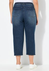 Džínové kuloty s tmavě modrým praním, elastickým pasem, zkrácenou délkou a dvěma zadními kapsami. Hladká textura, rovný střih nohavic.