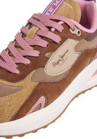 Brune og beige sneakers med rosa aksenter, materialer av semsket skinn og mesh, fremtredende snøring, og en hvit mellomsåle med teksturert gummisåle.