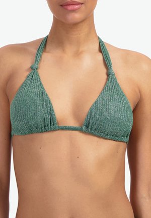 Femme portant un haut de bikini à col halter côtelé vert avec des liens ajustables et un tissu texturé sur un fond neutre.
