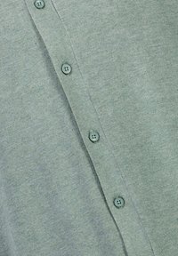 Grön stickad cardigan med en ribbad knäppning och sex matchande knappar. Mjuk textur med ett subtilt melerat mönster.