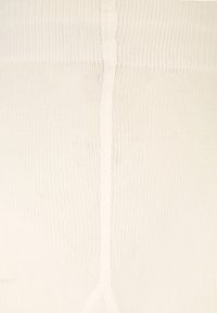 Collants blancs à côtes avec une texture lisse et une couture visible courant le long du centre. Fabriqués à partir d'un matériau extensible pour le confort.